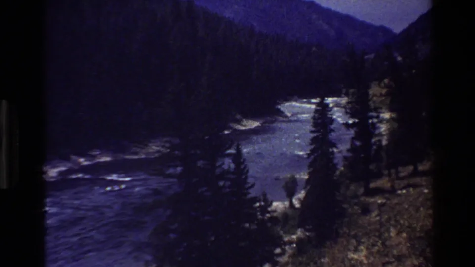 Grand Teton, Wyoming 8mm frame showing a mountain river corridor with rapids, forested slopes, and dark film edges.