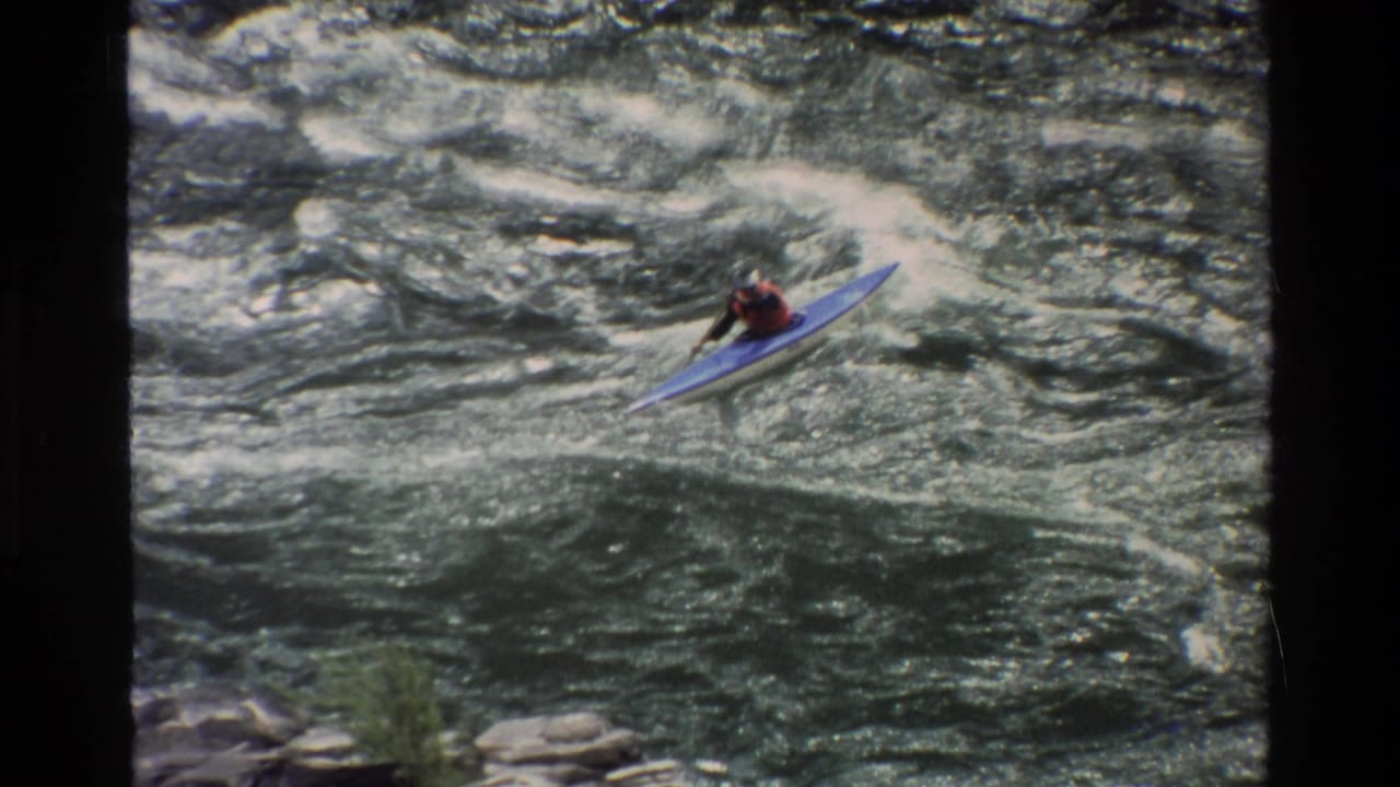 A kayaker in a blue boat navigates whitewater rapids in 1980 Grand Teton, Wyoming home-movie footage.