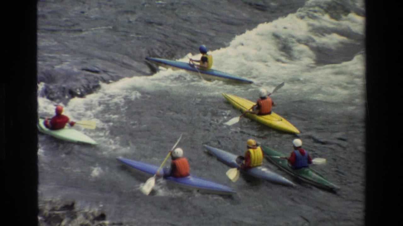 1980 Grand Teton, Wyoming 8mm frame showing helmeted kayakers in colorful boats approaching churning river rapids.