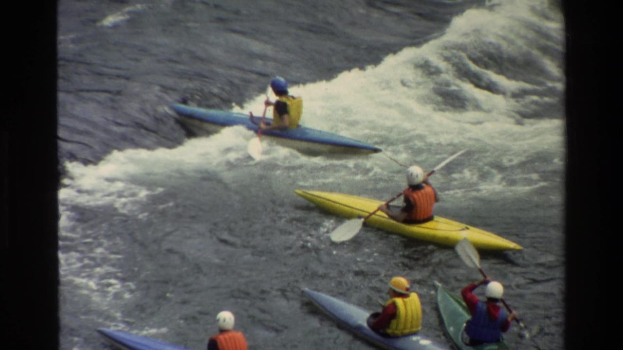 1980 Grand Teton, Wyoming frame with blue and yellow kayaks moving through whitewater while other paddlers wait nearby.