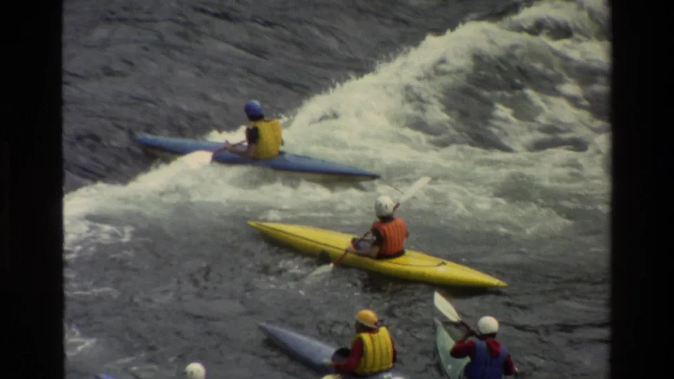 1980 Grand Teton, Wyoming 8mm frame showing a group of kayakers waiting and paddling near a whitewater feature.