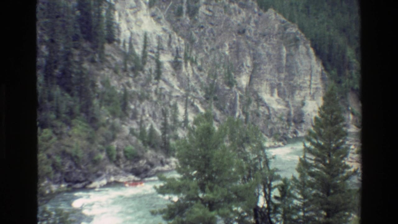 Whitewater river bends through a rocky canyon with a small orange raft.