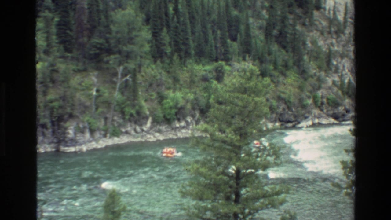 1980 8mm view of a distant orange raft entering whitewater on a green river in Grand Teton, Wyoming.