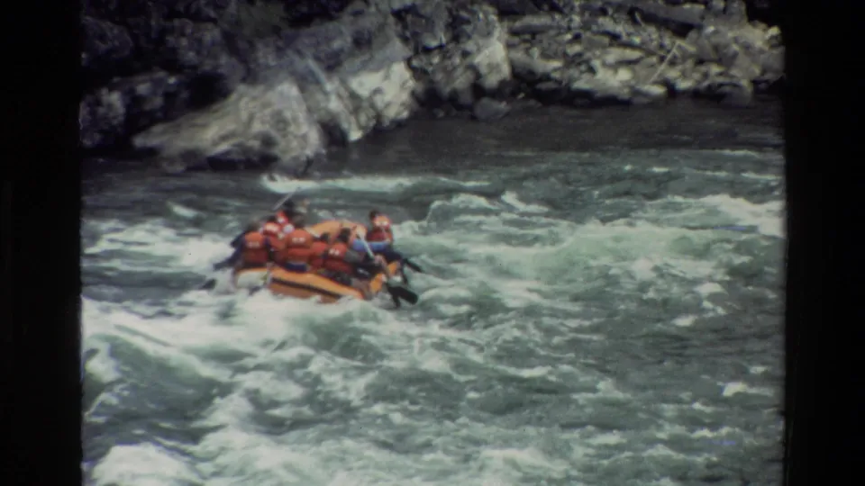 The raft angles across swirling whitewater as the rocky Grand Teton river setting remains in view.