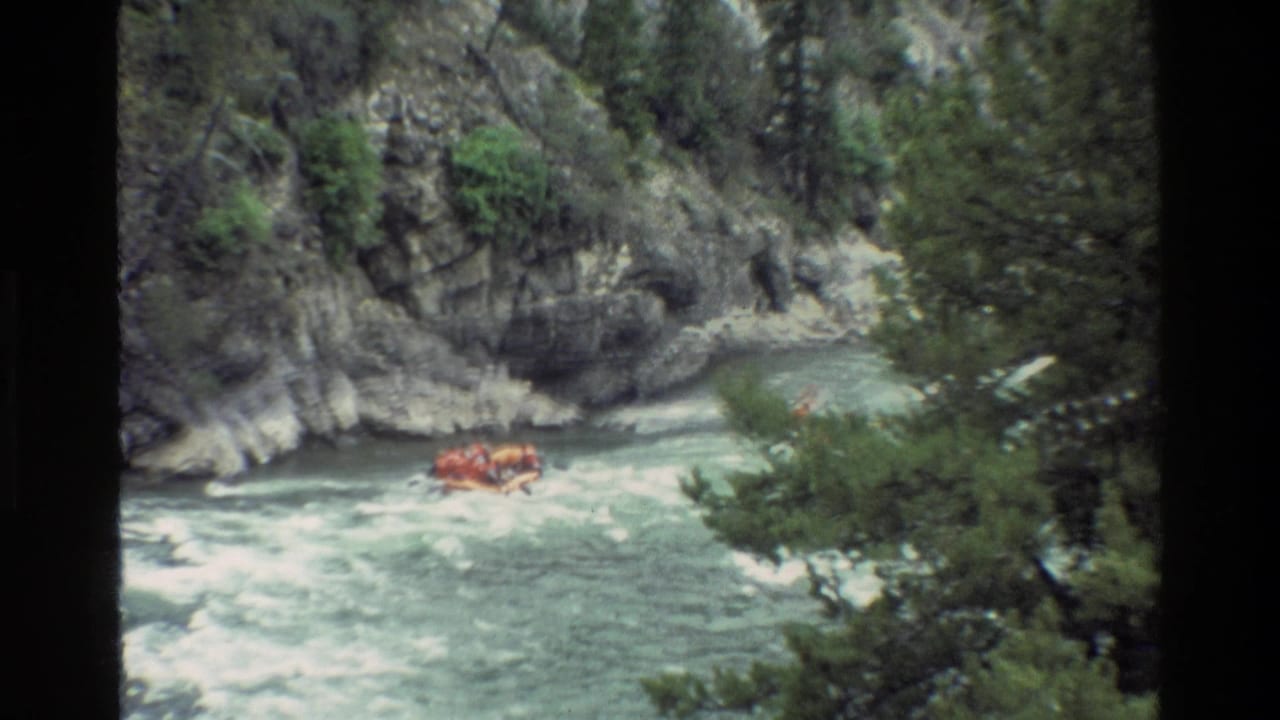 The raft appears farther downstream in Grand Teton, Wyoming, surrounded by whitewater, canyon rock, and riverside evergreens.