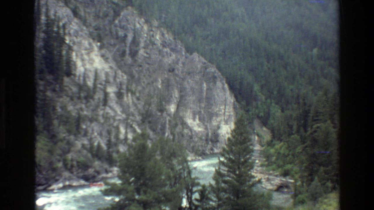 Mountain river canyon with forested slopes and whitewater visible below.
