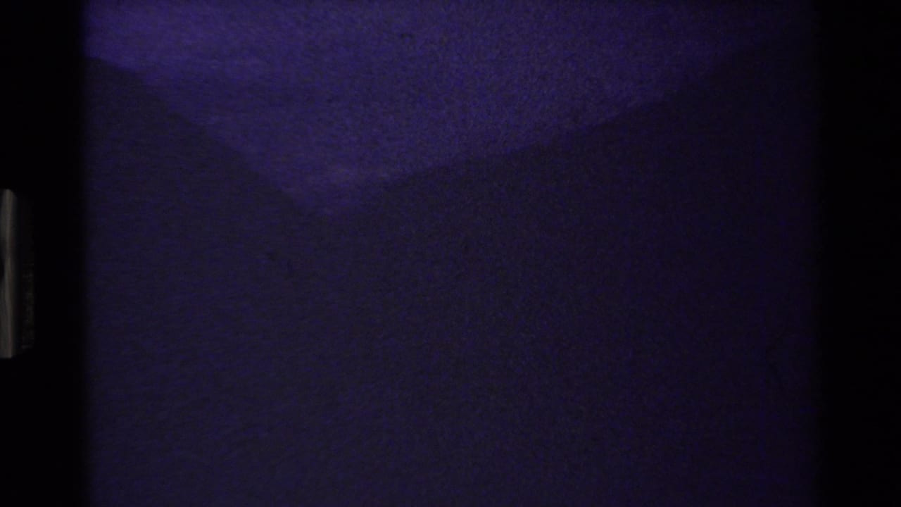 Underexposed 8mm transition frame with blue-purple cast and minimal readable subject detail.