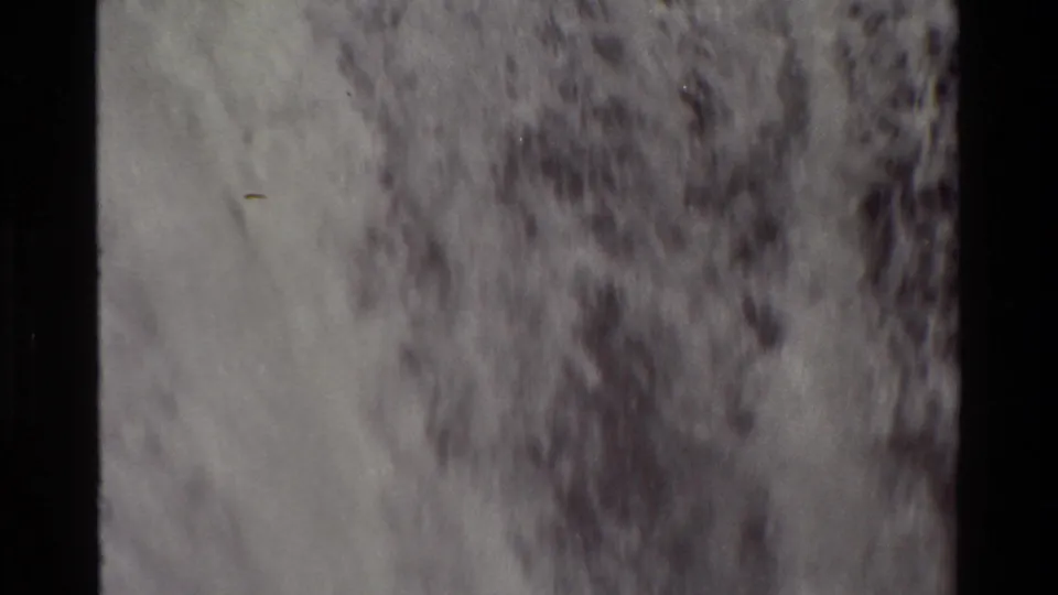 Close 8mm frame of the waterfall showing blurred vertical water movement and mottled dark rock or spray texture.