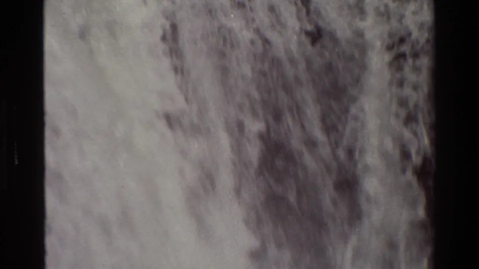 Final 1980 Grand Teton waterfall frame showing pale rushing water and darker textured areas in soft 8mm focus.