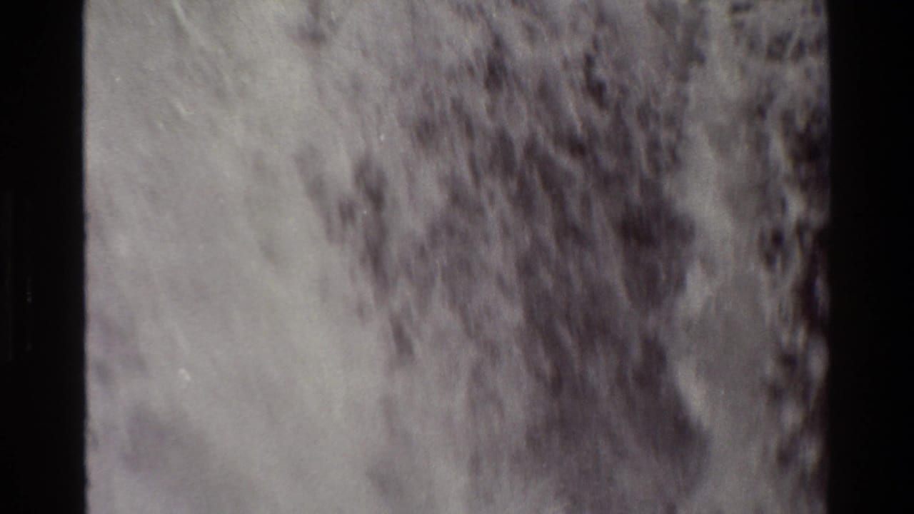 Soft 8mm frame of a waterfall dropping over dark rock into foaming water.