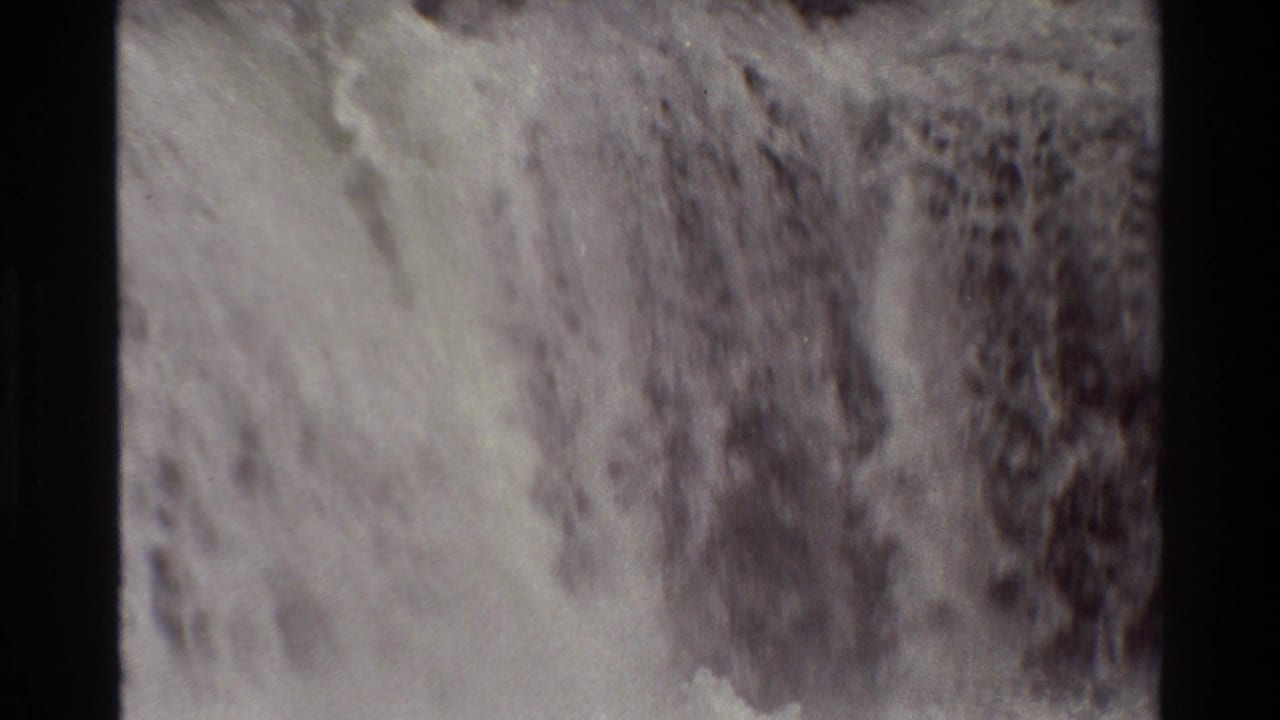 1980 Grand Teton frame shows white water cascading across dark rock, with small-gauge film grain and muted color.