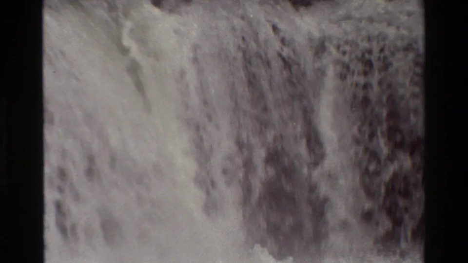 1980 Grand Teton frame shows white water cascading across dark rock, with small-gauge film grain and muted color.