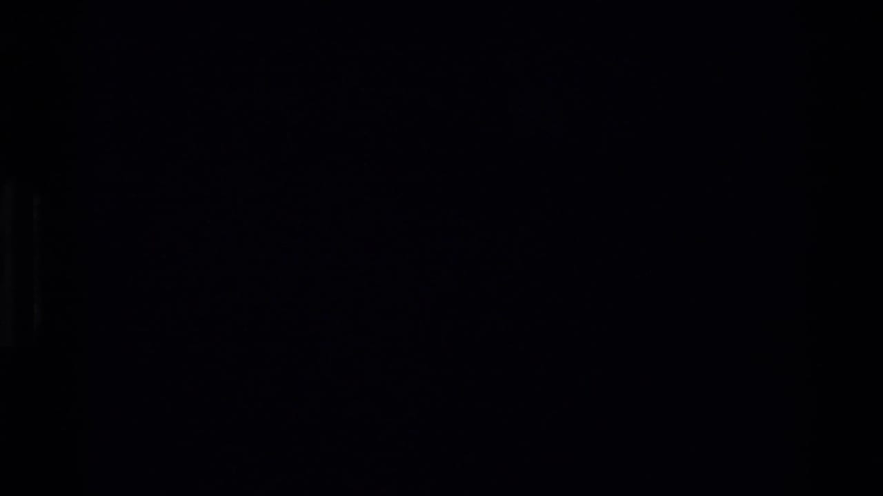 Underexposed 8mm frame from the Beale AFB sequence, with only faint structural shapes visible in heavy shadow.