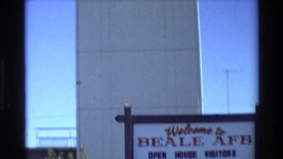 1981 Beale AFB home-movie frame showing an open-house welcome sign below the air traffic control tower wall.