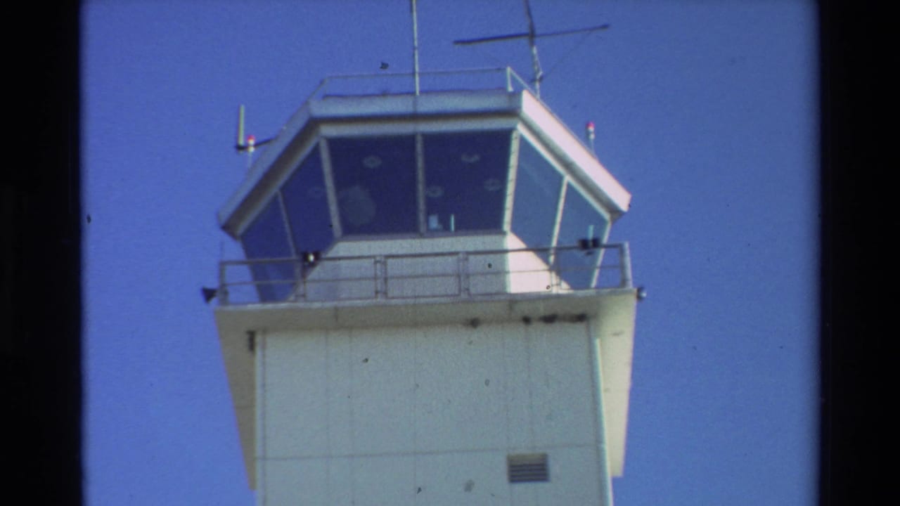 Beale AFB air traffic control tower filmed from a low angle in bright daylight, with antennas and railings visible.