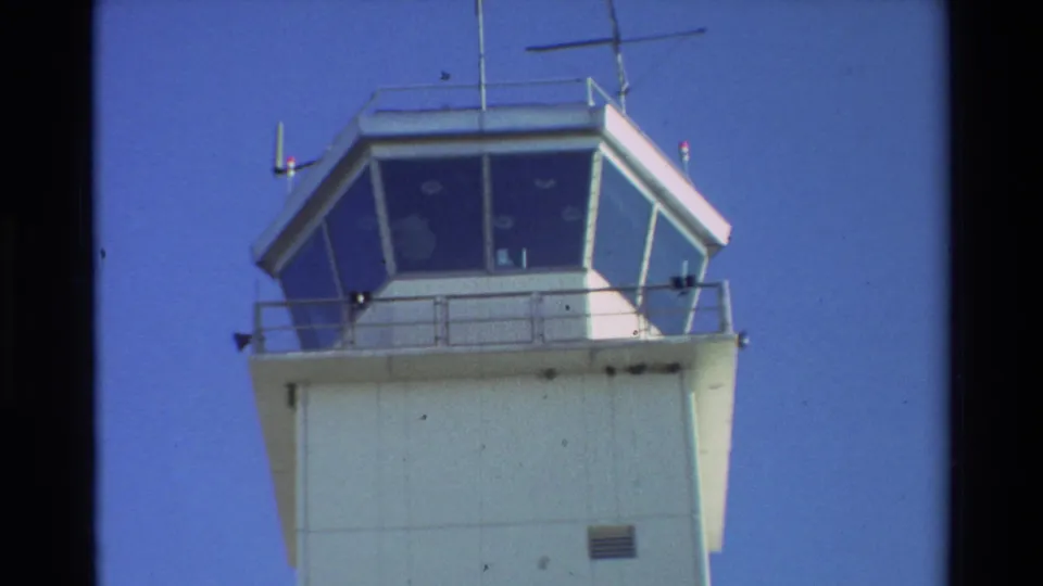 Beale AFB air traffic control tower filmed from a low angle in bright daylight, with antennas and railings visible.