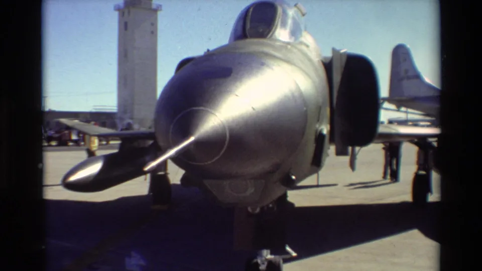 1981 Beale AFB frame showing a close nose view of an F-4 Phantom II on display with a control tower behind it.