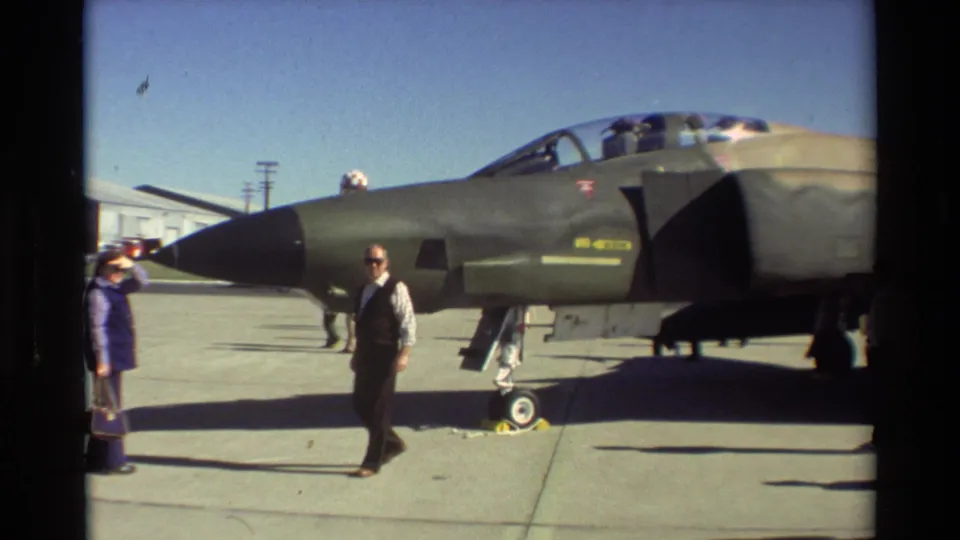 1981 Beale AFB frame showing civilians beside a camouflaged F-4 Phantom II during a tarmac aircraft display.