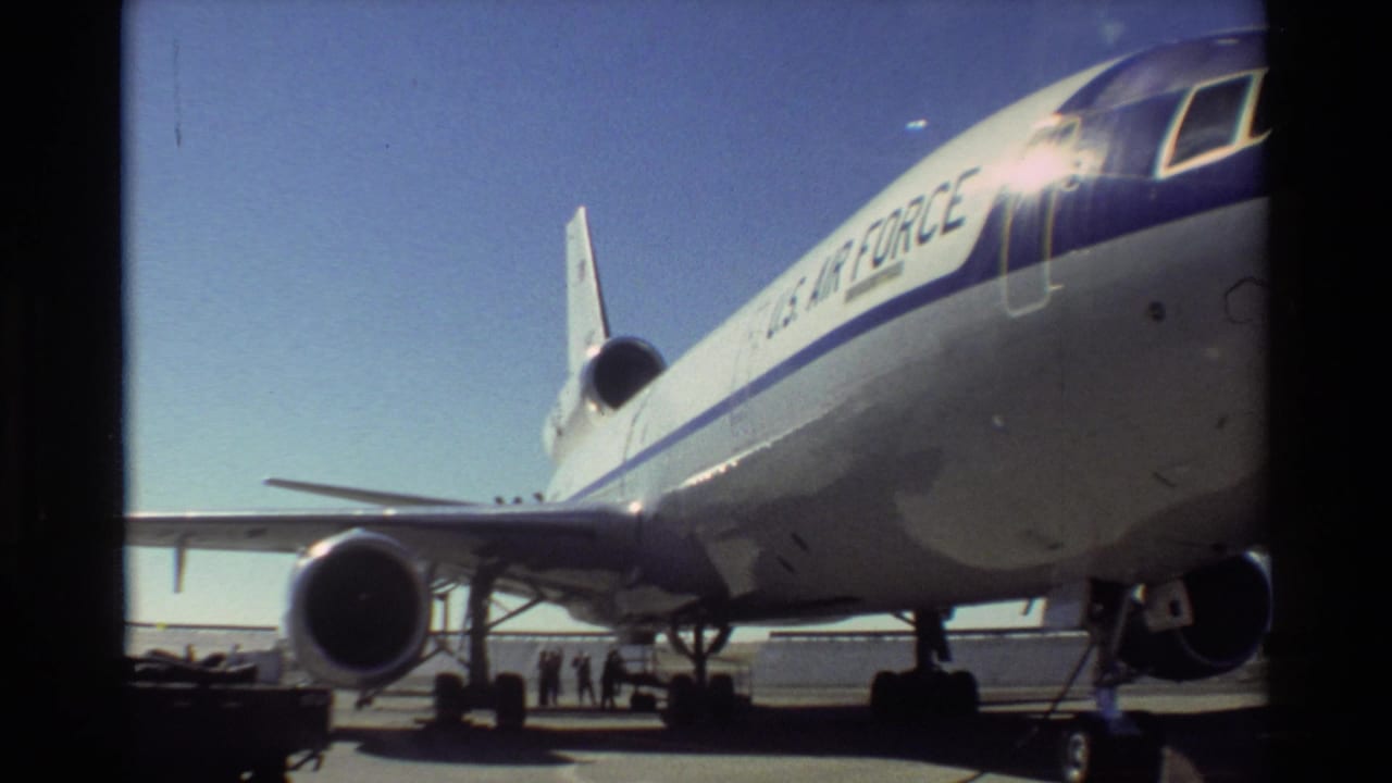 1981 Beale AFB 8mm frame showing a U.S. Air Force jumbo jet from the nose side, with engine, landing gear, and people on the tarmac.