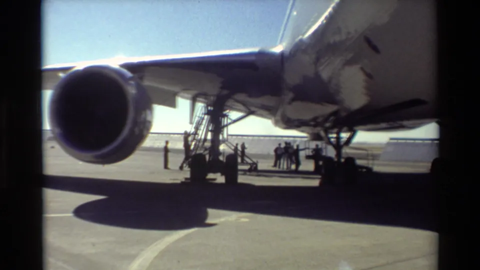 1981 Beale AFB 8mm frame centered on a large turbofan engine, with mobile stairs and a cluster of people beneath the aircraft wing.