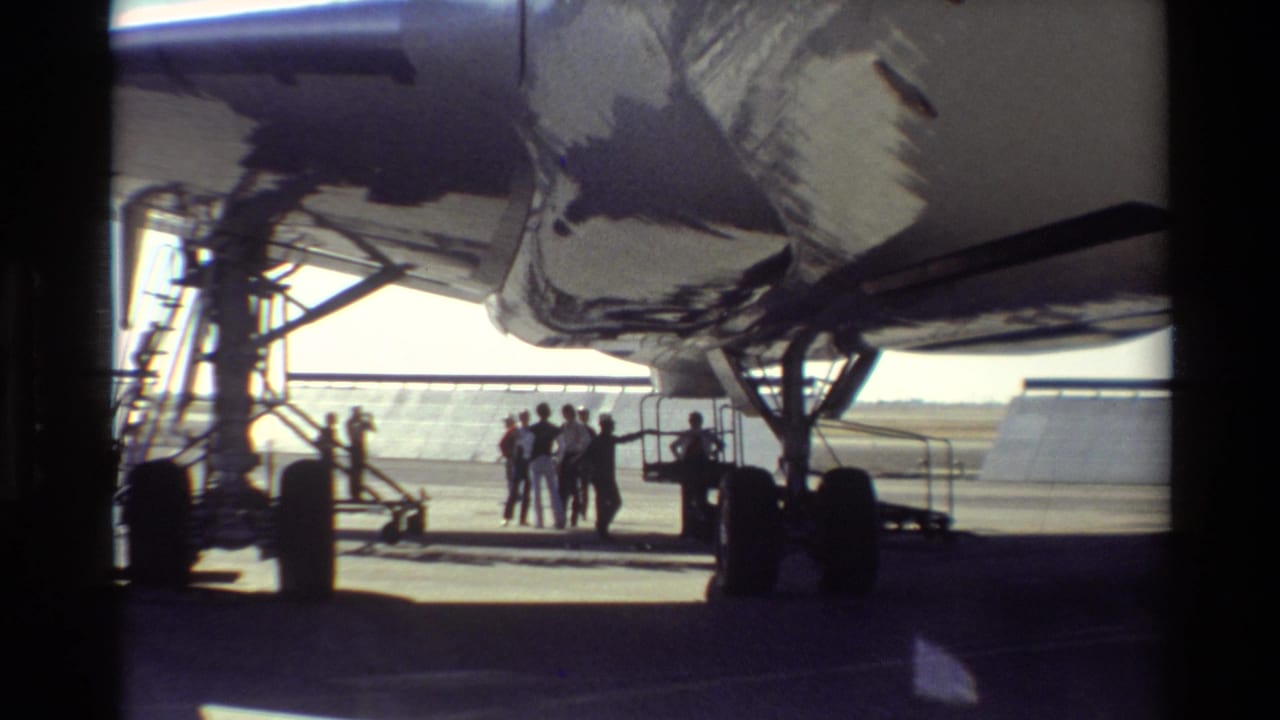 At Beale AFB in 1981, silhouetted people stand beneath a large aircraft wing on a sunlit tarmac.
