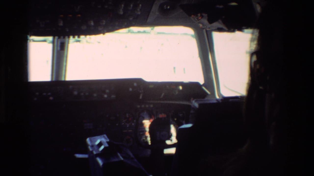 Dim cockpit view with pilot silhouette, instrument panel, and bright front windshield.