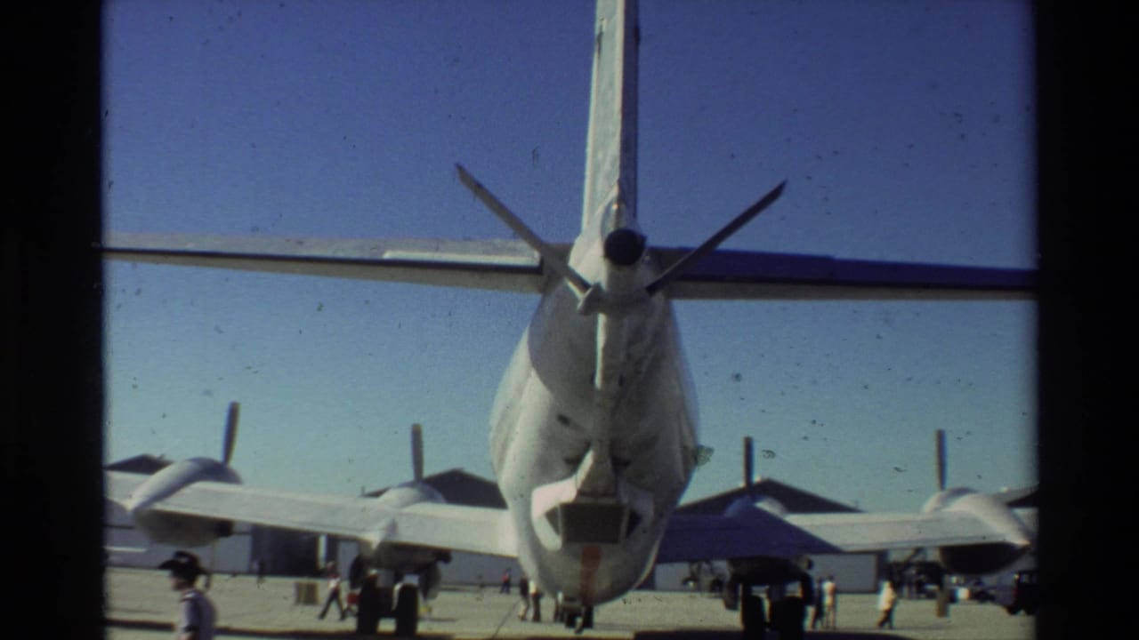 Rear view of a U.S. Air Force aircraft at Beale AFB in 1981, with propellers, tail assembly, and small figures on the tarmac.