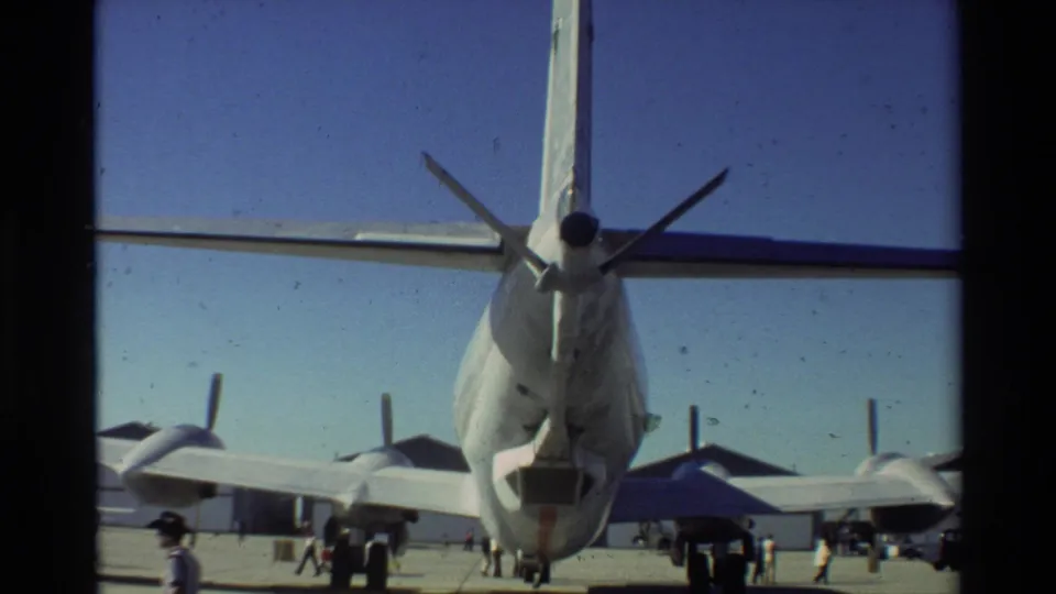 Rear view of a U.S. Air Force aircraft at Beale AFB in 1981, with propellers, tail assembly, and small figures on the tarmac.