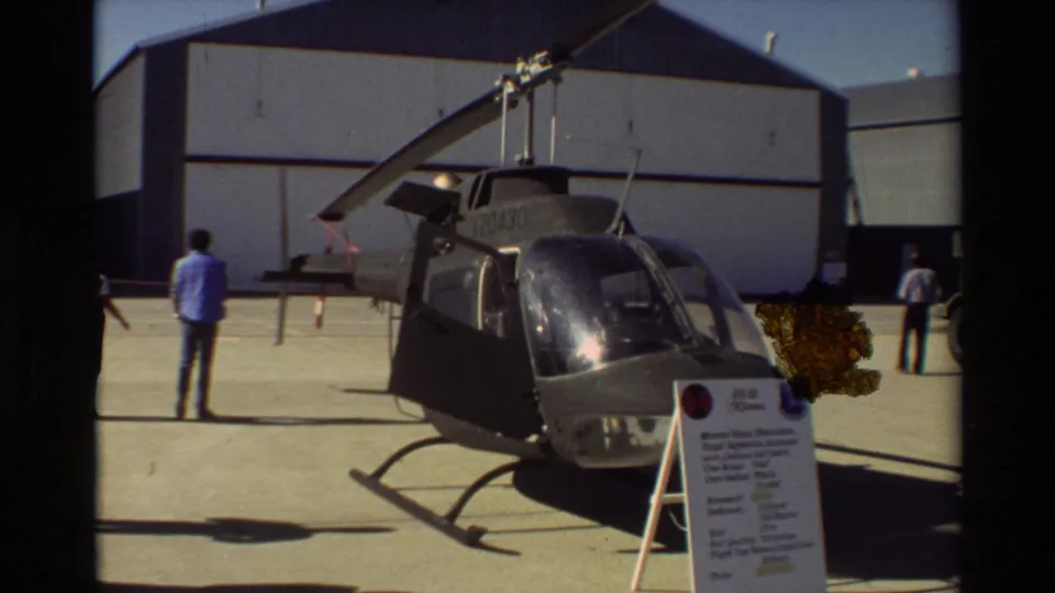 1981 Beale AFB tarmac scene with a military helicopter parked near a hangar and visitors or personnel around the aircraft.