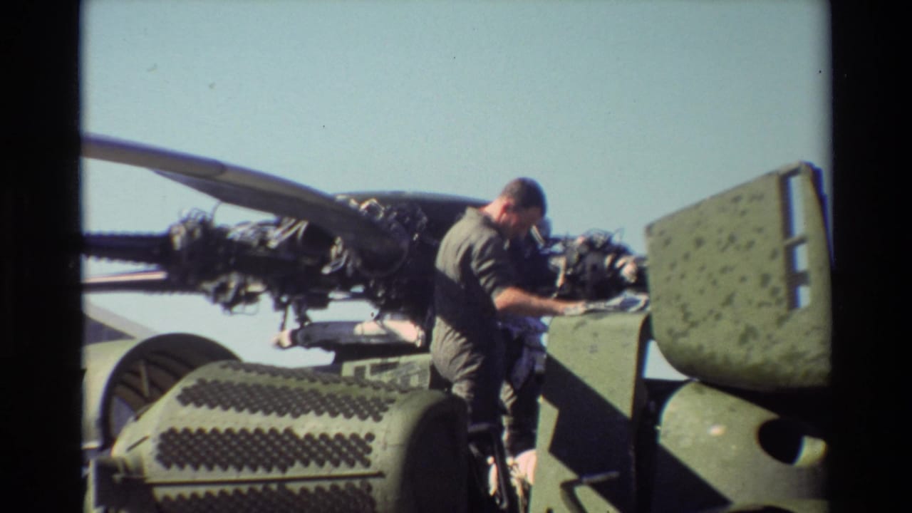 At Beale AFB in 1981, a uniformed man appears to inspect an exposed helicopter engine in bright daylight.