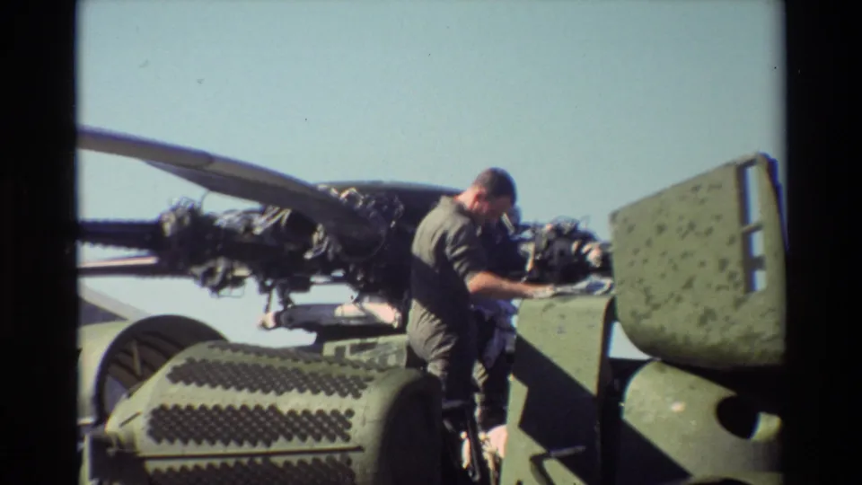 At Beale AFB in 1981, a uniformed man appears to inspect an exposed helicopter engine in bright daylight.