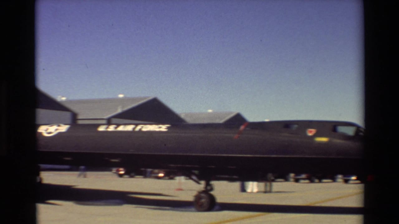 1981 Beale AFB home-movie frame showing the side of a parked SR-71 Blackbird with U.S. Air Force markings near hangars.