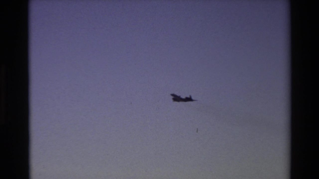 Distant aircraft silhouette over Beale AFB, California, in 1981 home-movie footage, framed by visible 8mm gate edges.