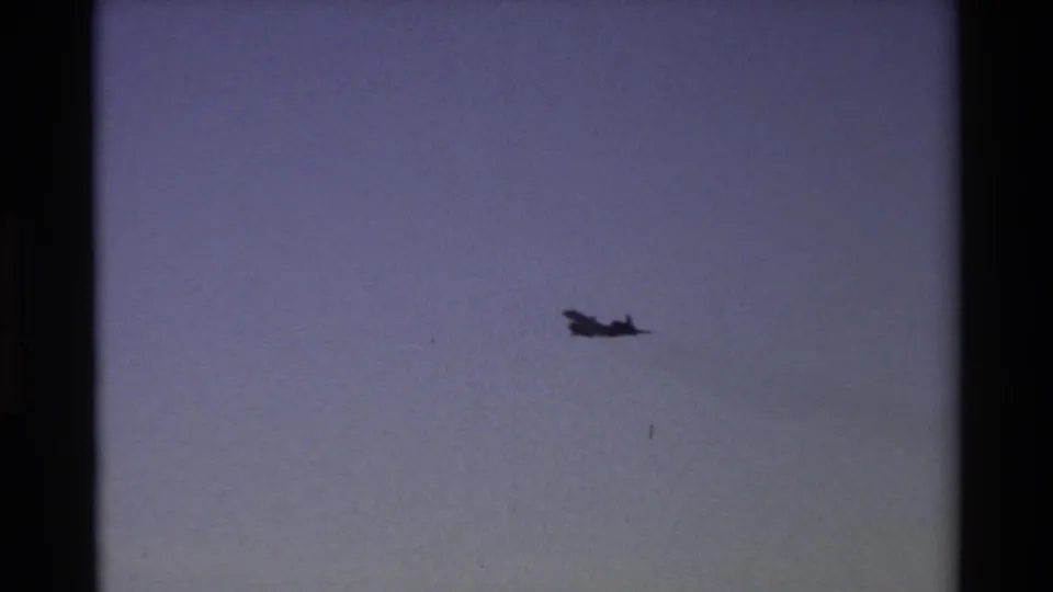 Distant aircraft silhouette over Beale AFB, California, in 1981 home-movie footage, framed by visible 8mm gate edges.