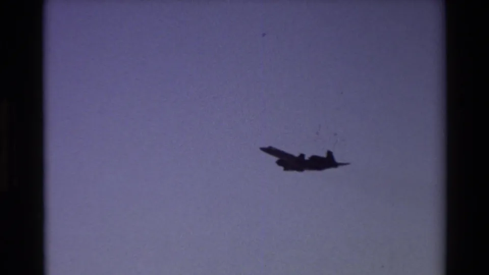 Military aircraft silhouette crosses the sky in 1981 Beale AFB 8mm footage, with soft exposure and dark frame borders.