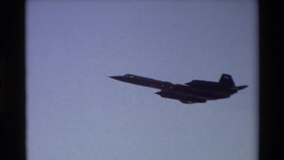 A sleek dark jet, likely an SR-71-type aircraft, flies across the 1981 Beale AFB frame in grainy 8mm footage.