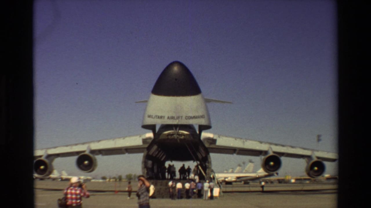 Front-rear view of a large military transport aircraft with visitors near the open ramp.