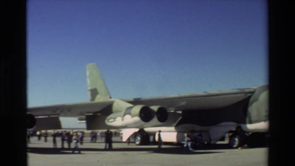 1981 Beale AFB home-movie frame with visitors under the wing and jet engines of a large Air Force aircraft.