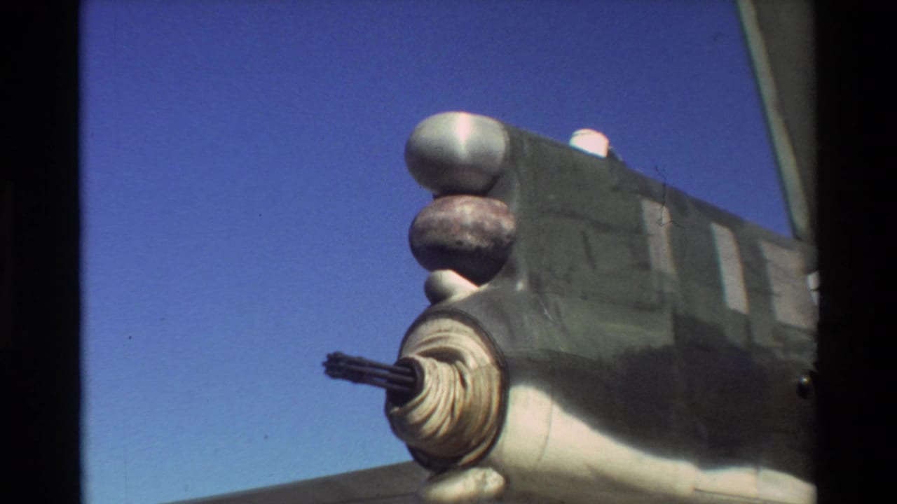 Close view of a military aircraft section with a protruding gun or turret against blue sky.