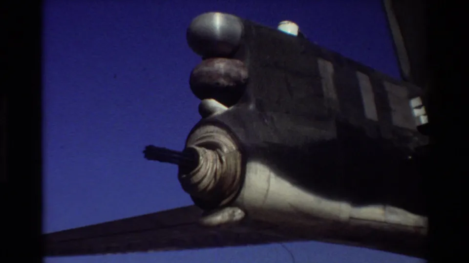 Darker 1981 Beale AFB 8mm frame showing the same military aircraft section with a protruding turret-like detail and blue sky.