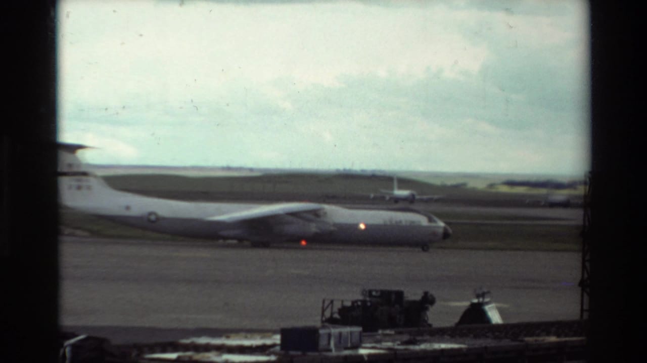 1981 Beale AFB footage appears to show a large military transport aircraft on the tarmac through a window frame.