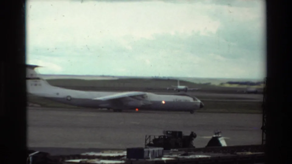 1981 Beale AFB footage appears to show a large military transport aircraft on the tarmac through a window frame.