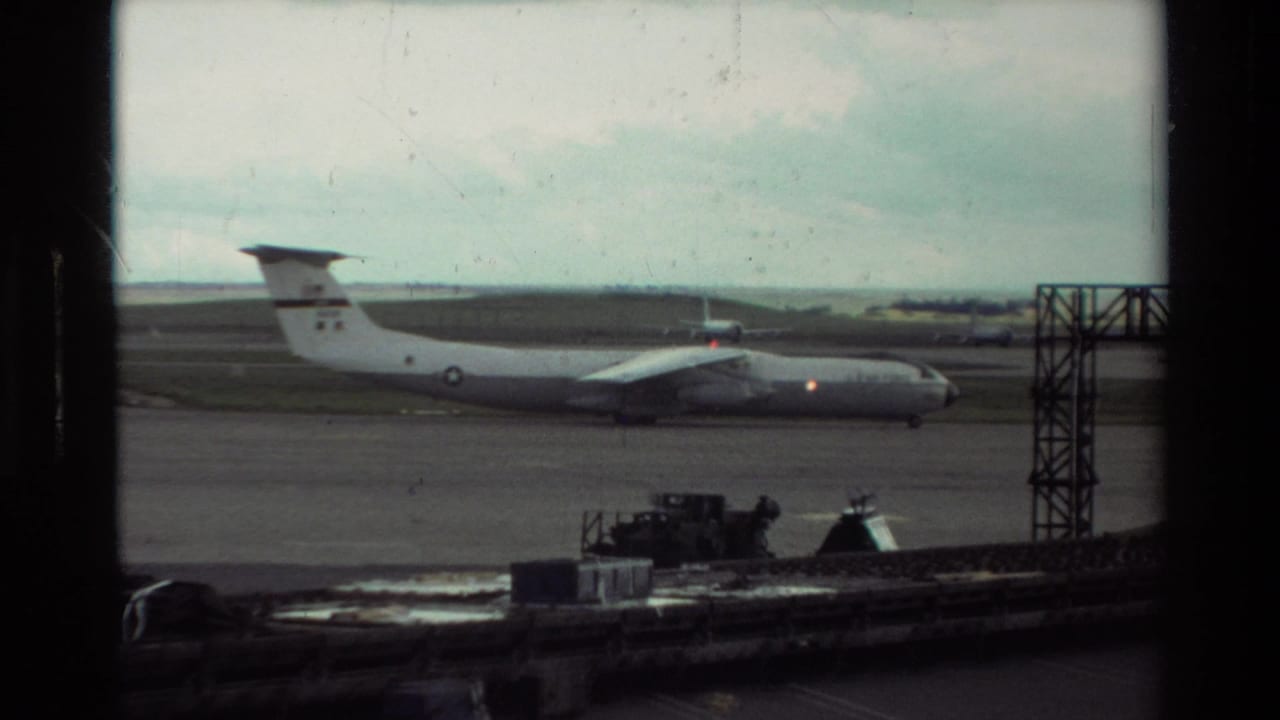 A large gray aircraft is visible on the Beale AFB tarmac, with service equipment and airfield structures in the foreground.