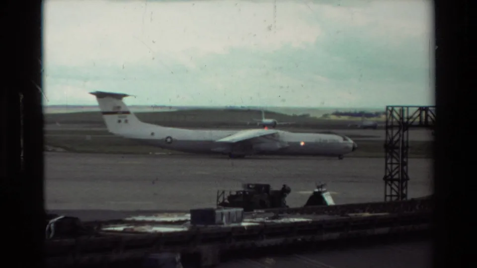 A large gray aircraft is visible on the Beale AFB tarmac, with service equipment and airfield structures in the foreground.