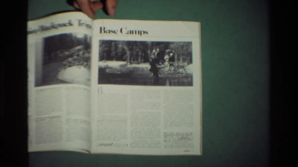 A hand holds open a magazine showing outdoor articles and black-and-white recreation photos, from archival 8mm footage dated 1981 in the metadata.