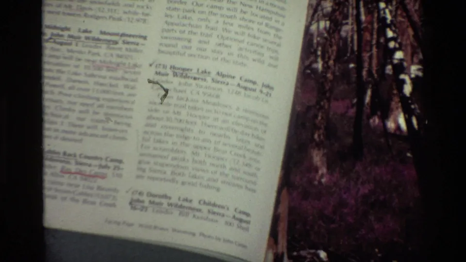 Close 1981 8mm view of a printed page with readable-looking but soft small text beside a cropped wooded photograph.