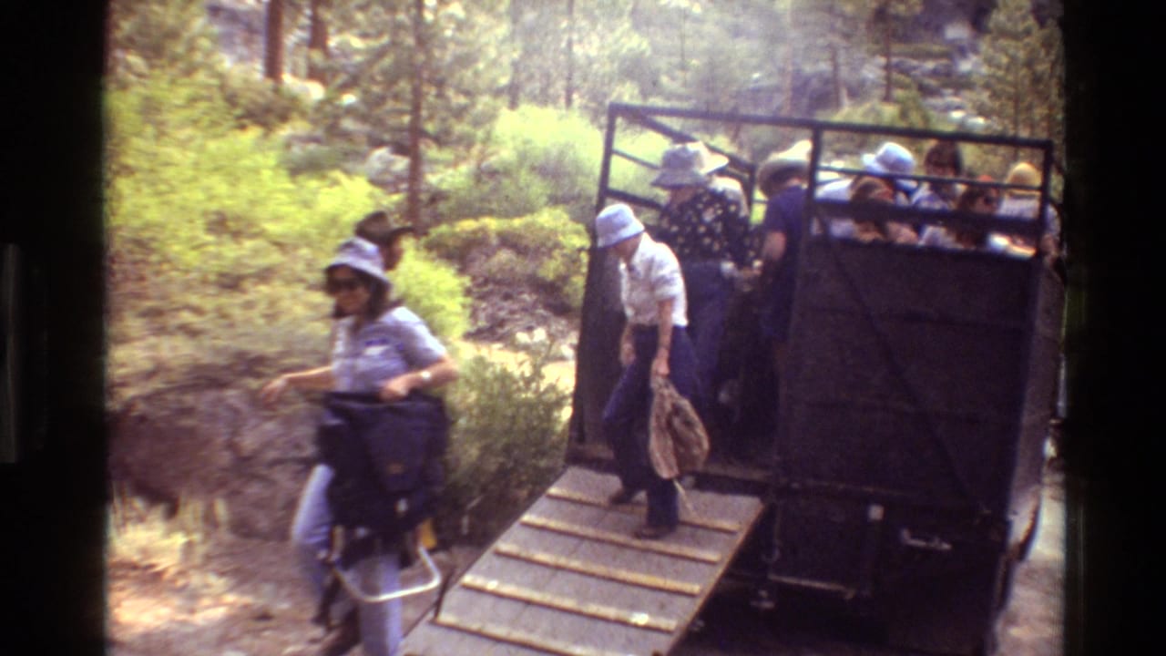 A hiker steps away from the truck ramp while others sit or stand in the open vehicle.
