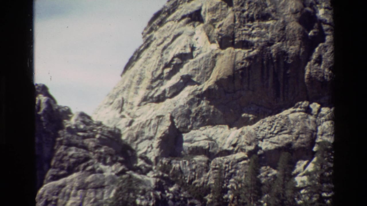 Close view of weathered rock face with pale sky behind it.
