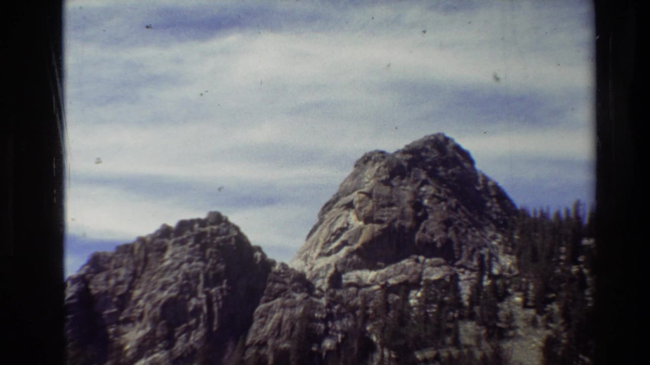Two rocky peaks with evergreen trees along the right slope.
