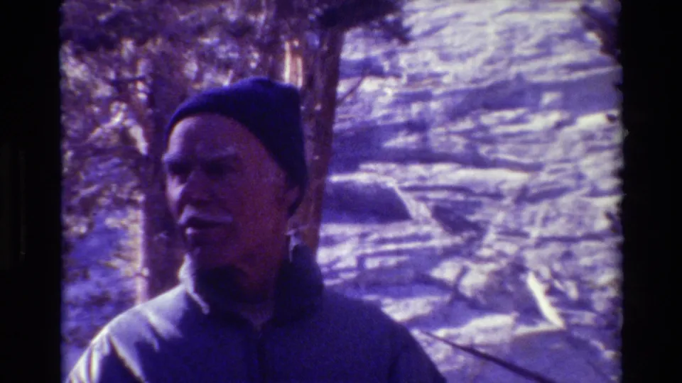 Close 8mm frame from 1981 showing an older man in a beanie looking aside in snowy British Columbia woods.